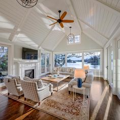 a large living room with white walls and ceiling fans in the center, along with wooden flooring