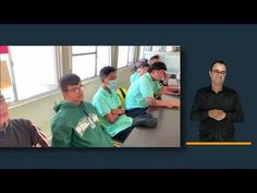 a group of kids sitting at desks in front of a man with glasses on