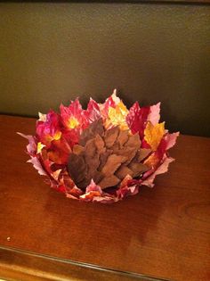 a vase filled with leaves on top of a wooden table