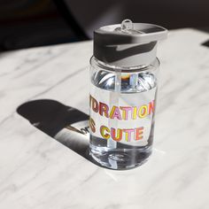 a water bottle sitting on top of a white table next to a shadow from a skateboard