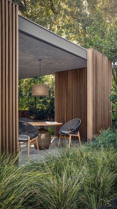 an outdoor dining area with chairs and table in the foreground, surrounded by tall grass