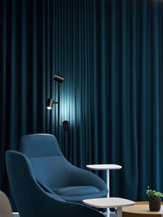 a blue chair and table in front of a curtained wall with lights on it