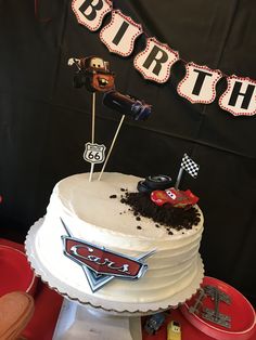 a birthday cake with dirt on top and race cars decorationating the cake for it's first birthday