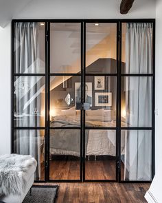 an open glass door leading to a bedroom with a bed in the corner and wooden floors