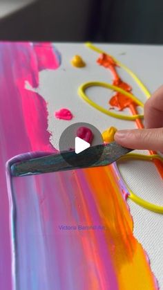 someone is painting with acrylic paint on the canvas and holding a pair of scissors