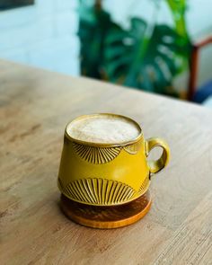 a yellow coffee cup sitting on top of a wooden table