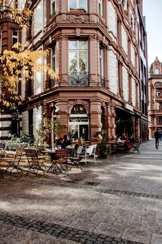 people sitting at tables in front of an old building on a cobblestone street