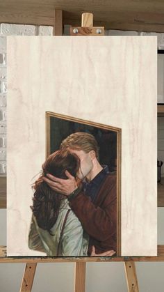 an easel with a painting of two people kissing