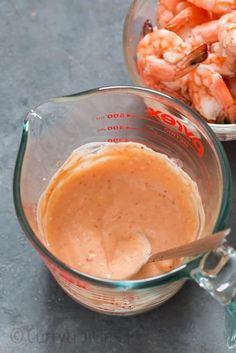 a glass bowl filled with sauce next to another bowl full of shrimp and carrots