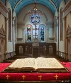 an open book sitting on top of a red blanket in front of a church alter