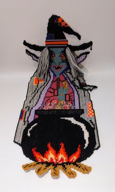 a knitted witch sitting in front of a fire