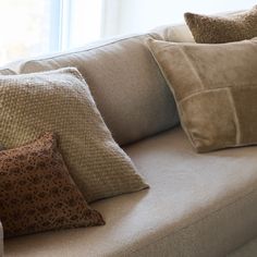 a couch with several pillows on it in front of a windowsill and a window sill