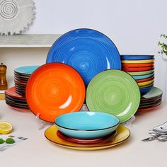 there are many different colored plates on the table