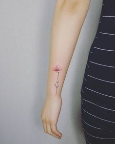 a woman's arm with a single flower tattoo on the left side of her arm