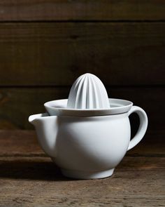 a white tea pot and saucer sitting on a wooden table next to each other