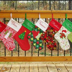 christmas stockings hanging on a rail with trees in the background