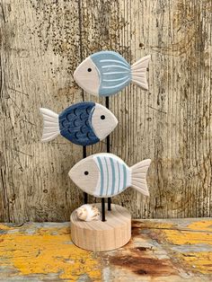 three blue and white fish sitting on top of a wooden stand