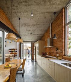 an open kitchen and dining room area with brick walls, wooden furniture and large windows