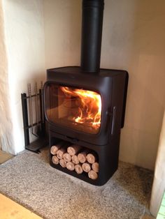 a wood burning stove in a living room next to a pile of fire pit logs