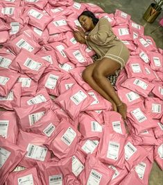 a woman laying on top of a pile of pink wrapped paper with white tags around her ankles