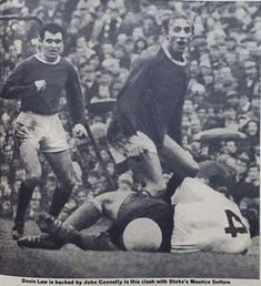 an old black and white photo of two soccer players on the ground with referee looking on