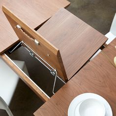 an open drawer on top of a wooden table next to a white plate and bowl