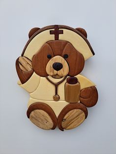 a wooden teddy bear with a cross on it's chest and holding a cup