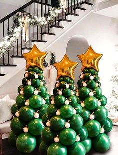 christmas tree made out of balloons in front of stairs with gold stars on top and green balls