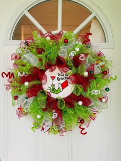 a christmas wreath on the front door with green and red mesh, decorated with letters