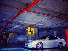 a silver car parked in a parking garage next to a yellow sign that says 2b