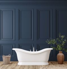 a white bath tub sitting on top of a wooden floor next to a potted plant