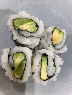 four pieces of sushi with cucumber in the middle on a white plate