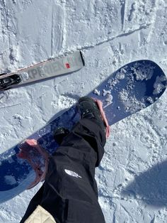 two snowboarders standing in the snow with their feet on one another's boards