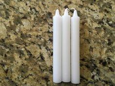 two white candles sitting next to each other on top of a marble countertopstone