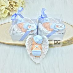 two baby shower items in a clear box on a white tablecloth with flowers and blue ribbon