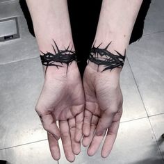 two hands with black crown tattoos on them