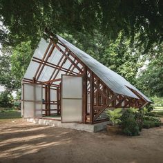 a house made out of wood and glass in the middle of a park with lots of trees