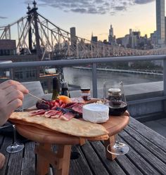 a person sitting at a table with food and wine in front of a cityscape