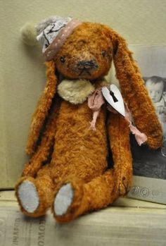 a brown stuffed animal sitting on top of a book shelf next to a wall with an old photo