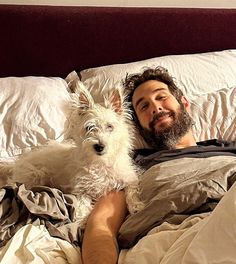 a man laying in bed with his dog