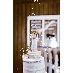 a wedding cake with a bride and groom figurine on top, surrounded by confetti