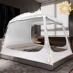 a white tent with lights on it in the middle of a room next to a bed