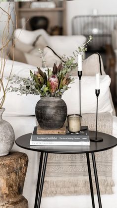 two vases with flowers and candles sit on a table in front of a couch