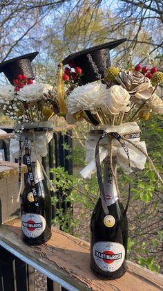 two bottles filled with flowers on top of a wooden rail