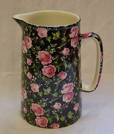 a black and pink flowered pitcher on a white background