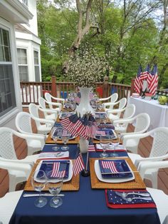 an outdoor table set with american flags and place settings