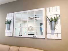 three mirrors are hanging on the wall with flowers in vases and one has a window pane