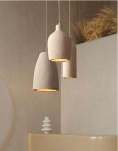 three white lights hanging from a ceiling in a room with beige walls and flooring