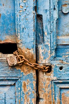 an old blue door with a chain attached to it