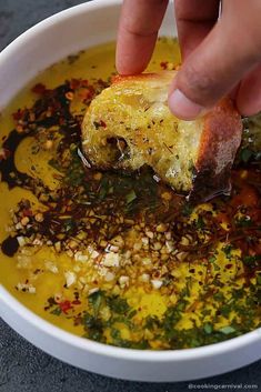 a person dipping something into a bowl of soup